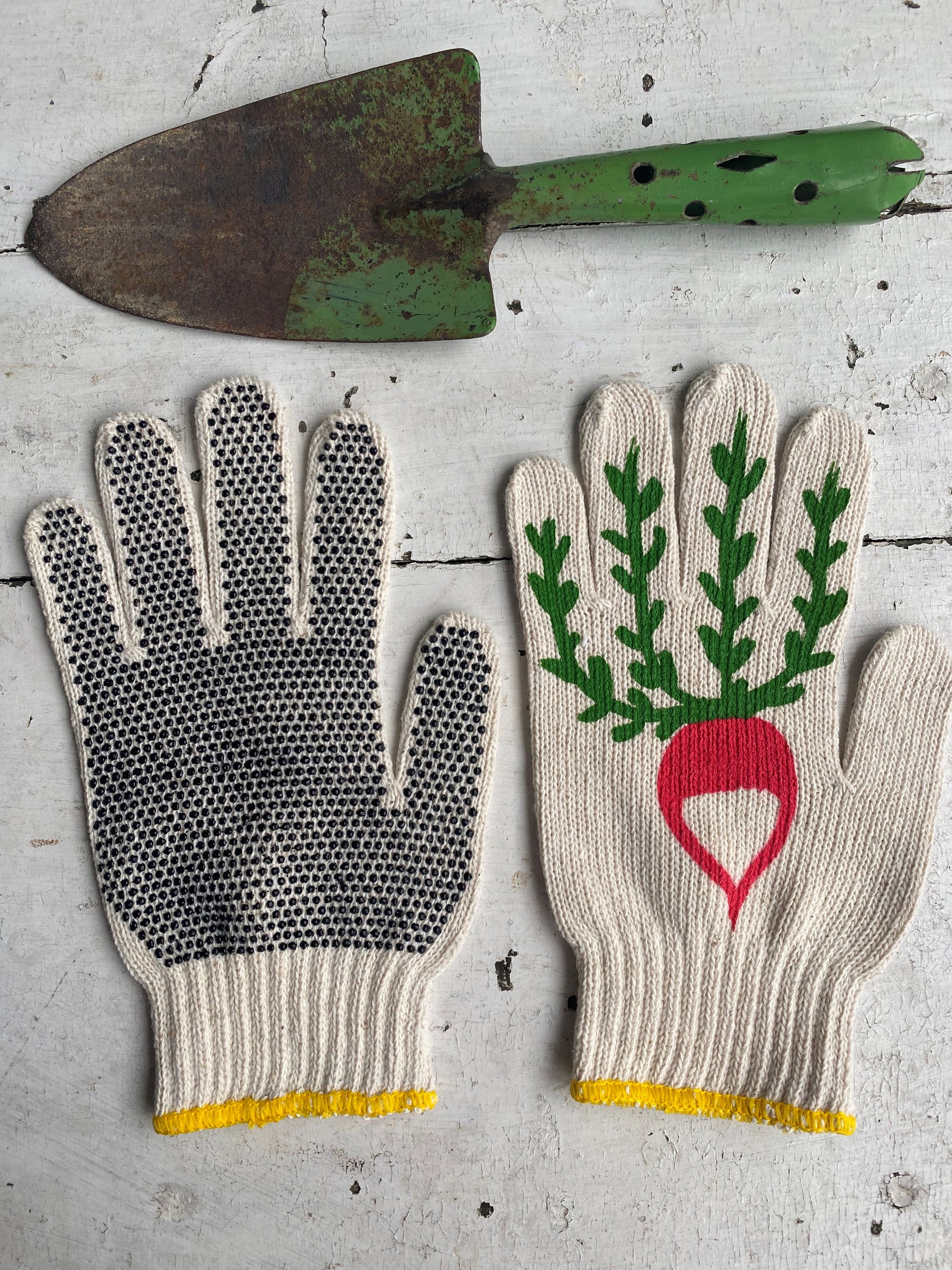 pair of hand painted radish gardening gloves and vintage shovel as a prop